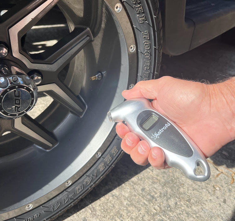 man holding golf cart tire pressure gauge by golf cart tire